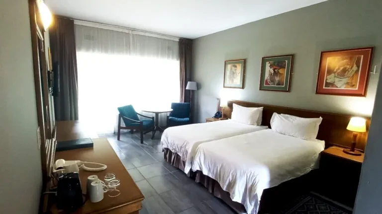 room with twin beds, table and chairs, coffee station and TV