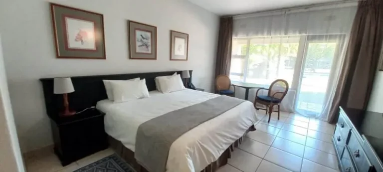 room in a lodge with a bed, table and two chairs and cabinet