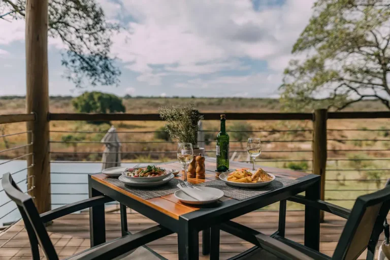 outside dining area with a table and chairs overlooking a watering hole