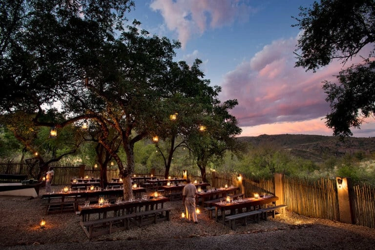 Outside boma area covered with trees, benches and tables with candles